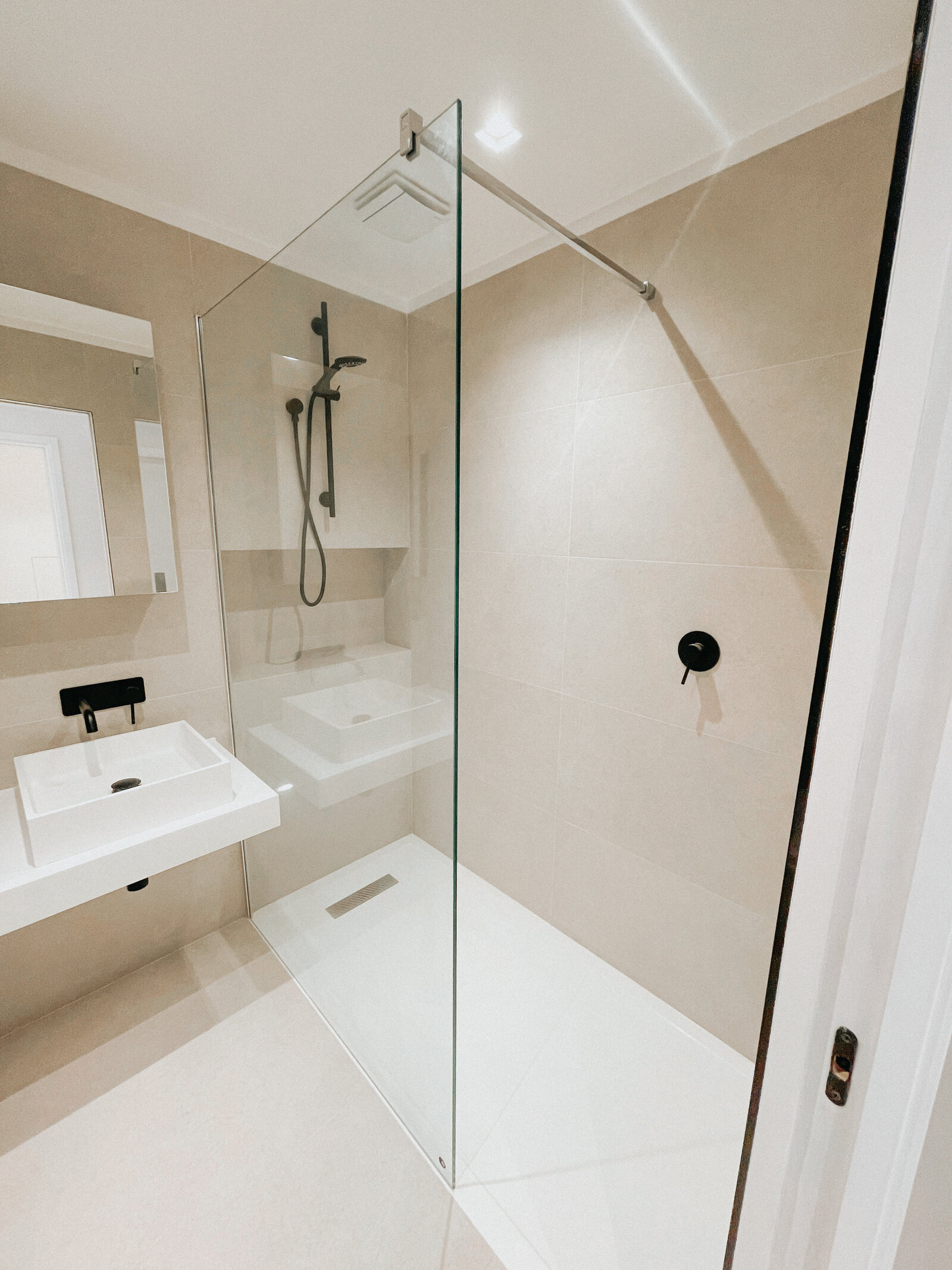 A shower room with a glass screen and wall-hung basin