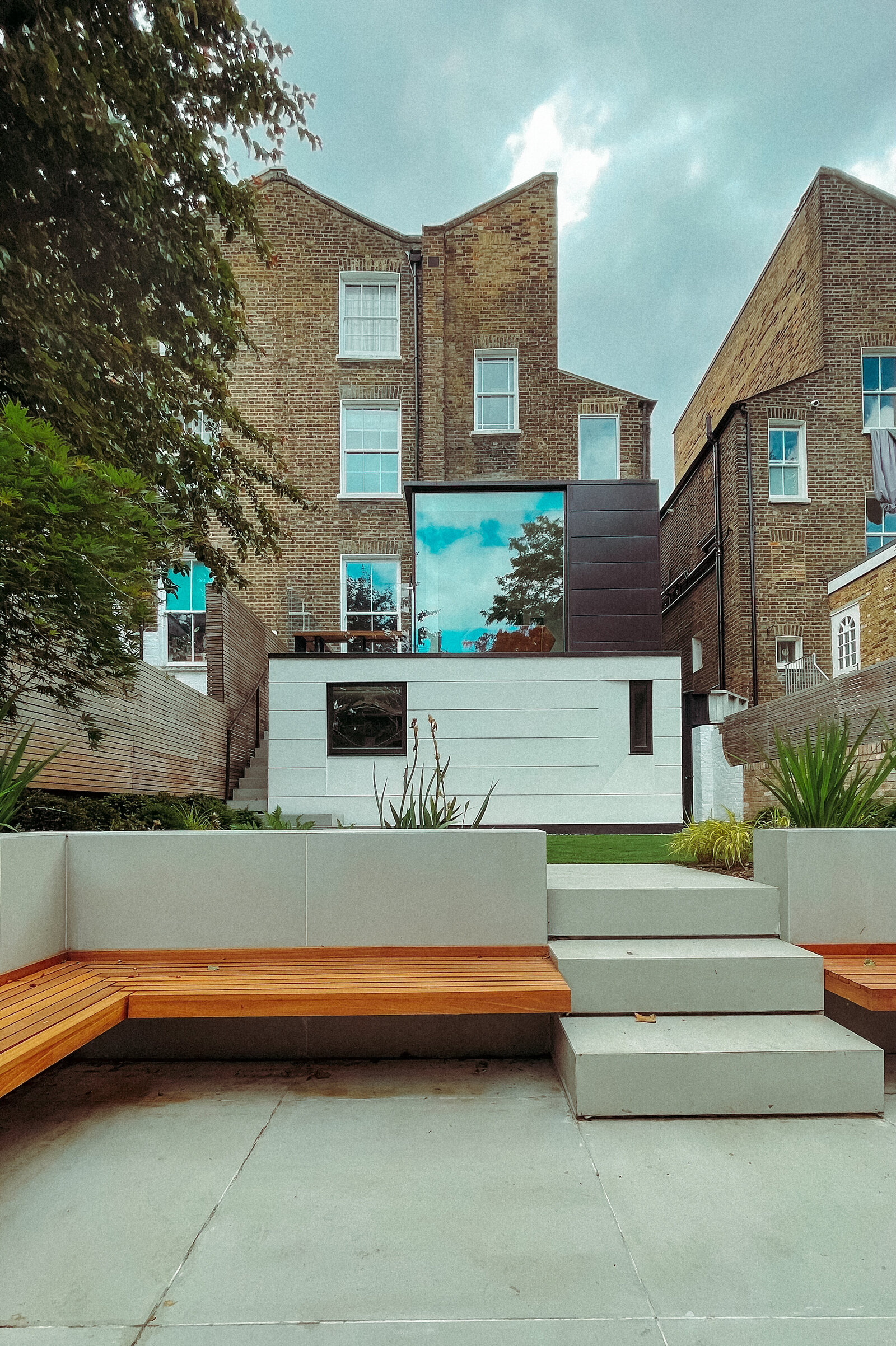 A rear extension in white render and dark cladding, with a landscaped garden