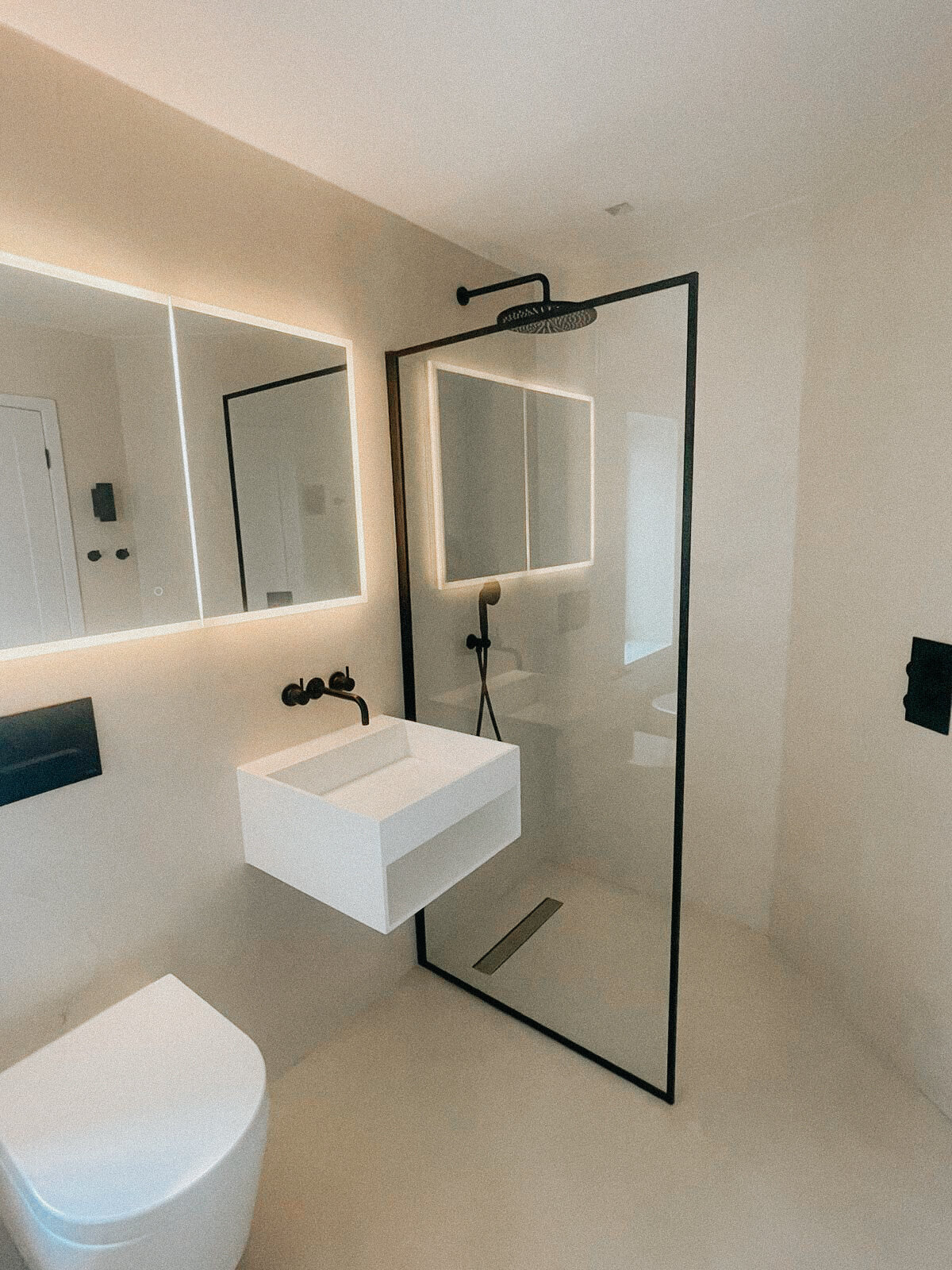 Hansler: a pale bathroom with a black-framed glass shower